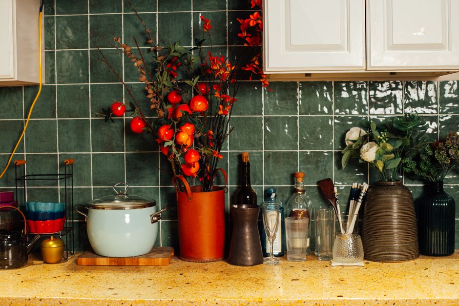 A vibrant kitchen counter setup featuring colorful bowls, kitchenware, and floral arrangements.